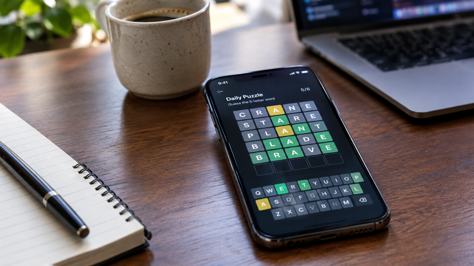 Smartphone displaying a five-letter Wordle-style puzzle with green, yellow, and gray tiles on a desk